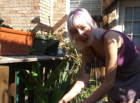 Skinny blonde in a skirt Sylvie J flashing her pussy in an indoor garden