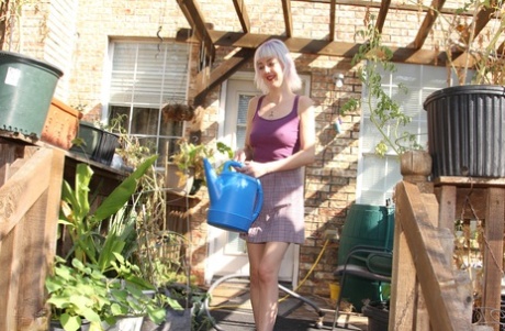 Skinny blonde in a skirt Sylvie J flashing her pussy in an indoor garden