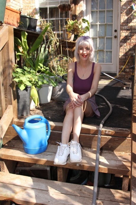 Skinny blonde in a skirt Sylvie J flashing her pussy in an indoor garden