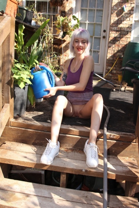 Skinny blonde in a skirt Sylvie J flashing her pussy in an indoor garden