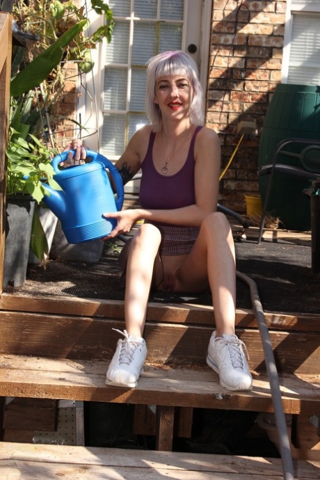 Skinny blonde in a skirt Sylvie J flashing her pussy in an indoor garden